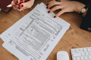 Top view of a business professional checking tax documents on a wooden desk.